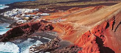 Kleines Dorf an der Küste mit Vulkanlandschaft auf Lanzarote