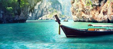 Traditionelles Ruea Hang Yao auf türkisfarbenem Wasser vor Kalksteinfelsen in Krabi, Thailand.