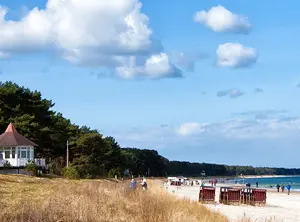Ostsee-Szenerie: Sandstrand, Promenade und Strandkörbe auf der Insel Rügen unter blauem Himmel.