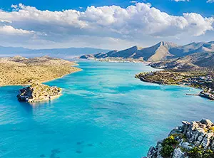 Baie turquoise entourée de collines rocheuses et de végétation méditerranéenne