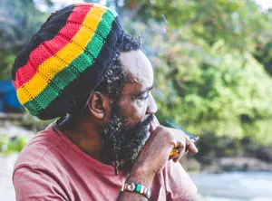 Homme avec bonnet coloré de style rasta assis en extérieur