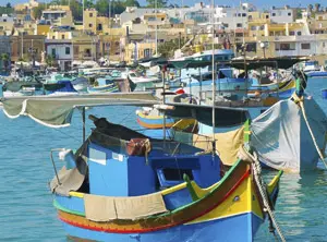 Bateaux de pêche colorés dans un port avec maisons en arrière-plan à Malte
