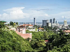 Panoramablick auf Lapu Lapu City, Cebu, mit modernen Hochhäusern und grünen Hügeln im Vordergrund.