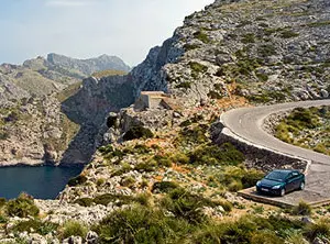 Route sinueuse du cap de Formentor à Majorque, longeant des falaises rocheuses au-dessus de la mer sous une lumière méditerranéenne.