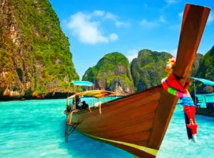 Bateau traditionnel en bois sur une eau turquoise avec des falaises rocheuses couvertes de végétation