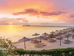 Plage paisible à Marsa Alam au coucher du soleil avec parasols et mer Rouge