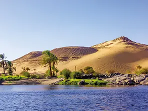 Paysage du Nil entre rive verdoyante et dunes désertiques en Égypte