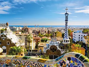 Vue sur le parc Güell à Barcelone, avec ses mosaïques colorées et la ville s’étendant jusqu’à la mer Méditerranée.