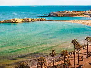 Plage de Monastir avec eau turquoise, palmiers et baie méditerranéenne