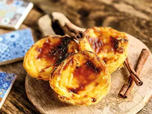 Pastéis de nata dorés servis sur une assiette en bois