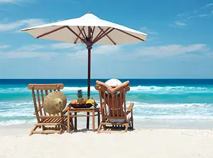 Chaises longues et parasol sur une plage de sable fin à Majorque, face à une mer turquoise.