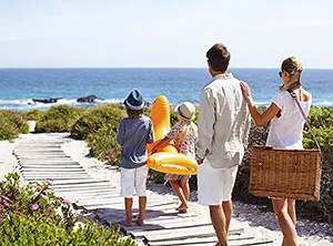 Familie mit Kindern auf einem Weg zum Strand mit Meer im Hintergrund