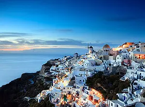 Weisse Häuser und blaue Kuppelkirchen in Oia auf Santorini bei Abendstimmung