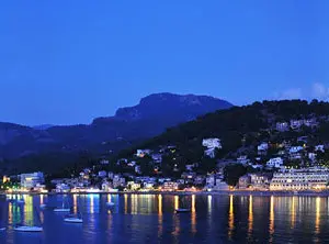 Hafen von Port de Sóller am Abend mit beleuchteter Uferpromenade und Spiegelungen im Wasser