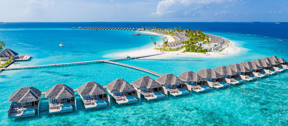 Malediven: Ansicht gebogene Resort-Insel mit Palmen und vielen kleinen Strandhäusern